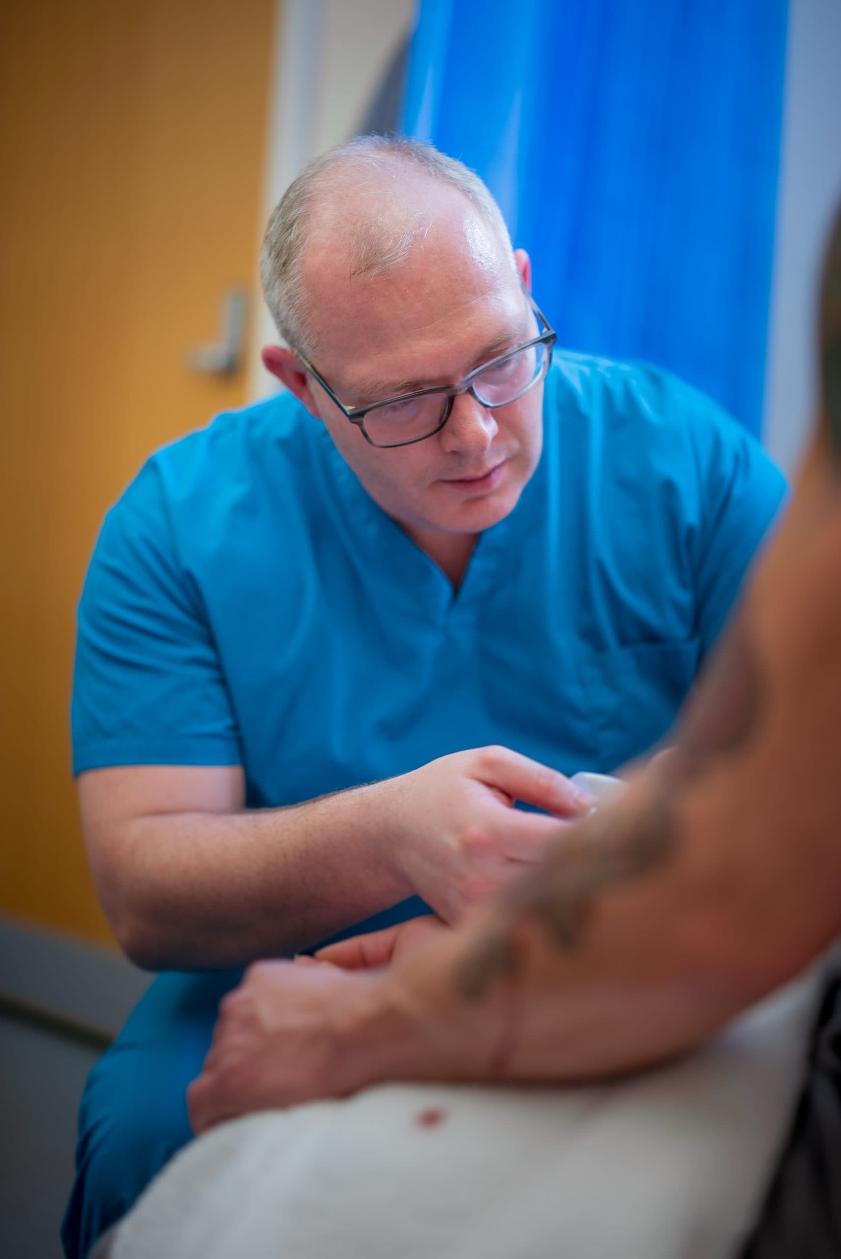 Doctor examining patient's arm in clinic